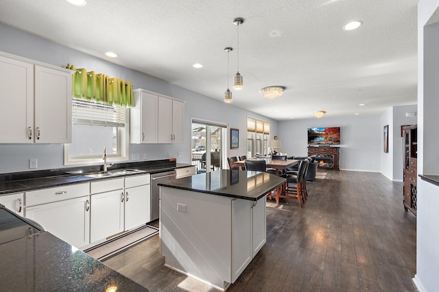 kitchen with white cabinets, dishwasher, open floor plan, and a sink