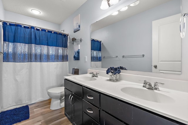 bathroom featuring a textured ceiling, wood finished floors, a sink, and toilet