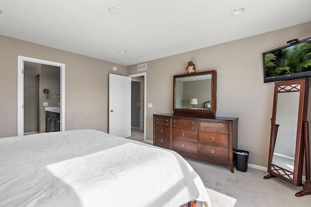 bedroom featuring visible vents, ensuite bath, light carpet, and baseboards