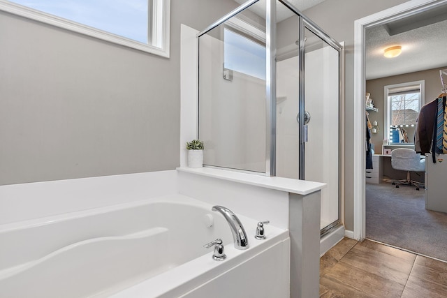 full bath featuring a textured ceiling, a shower stall, and a bath