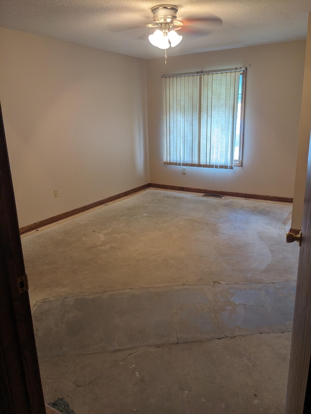 empty room with concrete flooring, ceiling fan, a textured ceiling, and baseboards