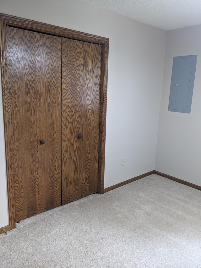 unfurnished bedroom with carpet, electric panel, and baseboards