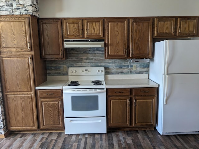 kitchen with dark wood finished floors, light countertops, decorative backsplash, white appliances, and under cabinet range hood