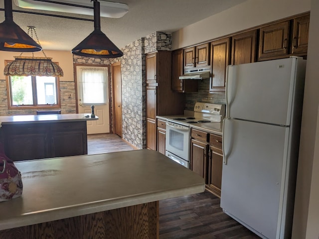 kitchen featuring white appliances, under cabinet range hood, dark wood-style flooring, and a textured ceiling