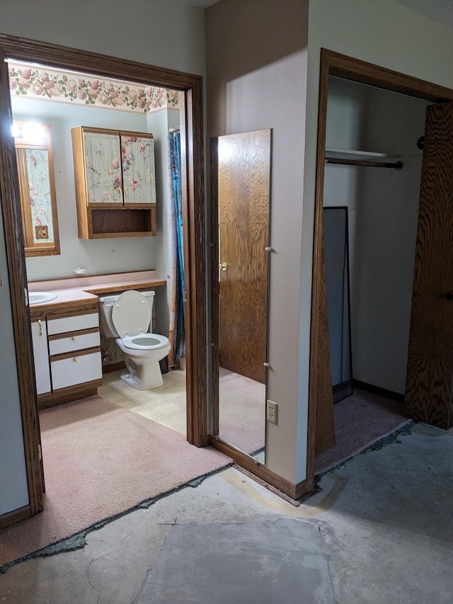 bathroom featuring toilet, baseboards, and vanity