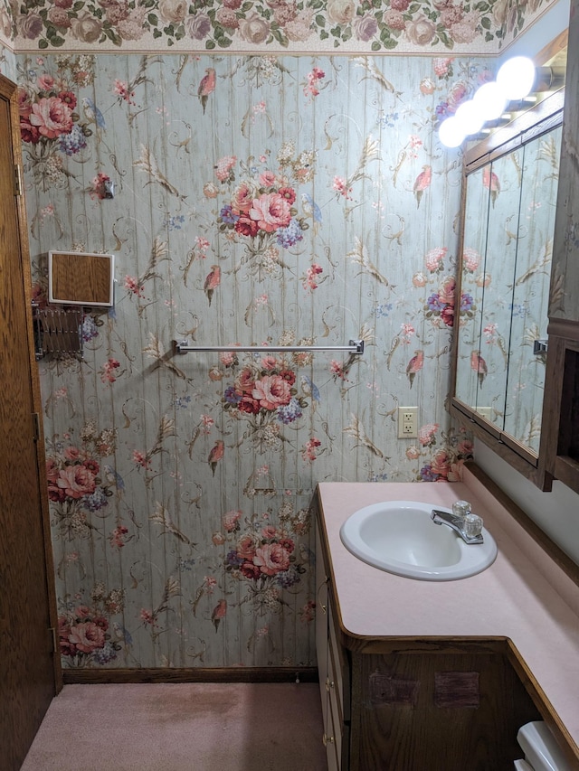 half bathroom featuring vanity and wallpapered walls