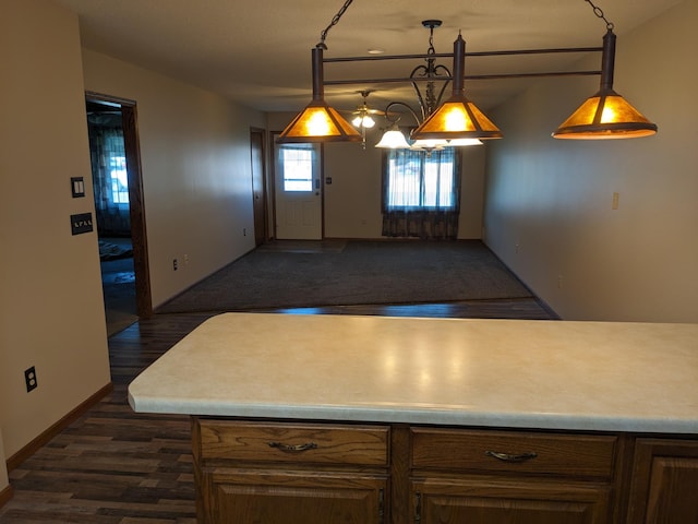 kitchen with hanging light fixtures, light countertops, and dark wood-type flooring