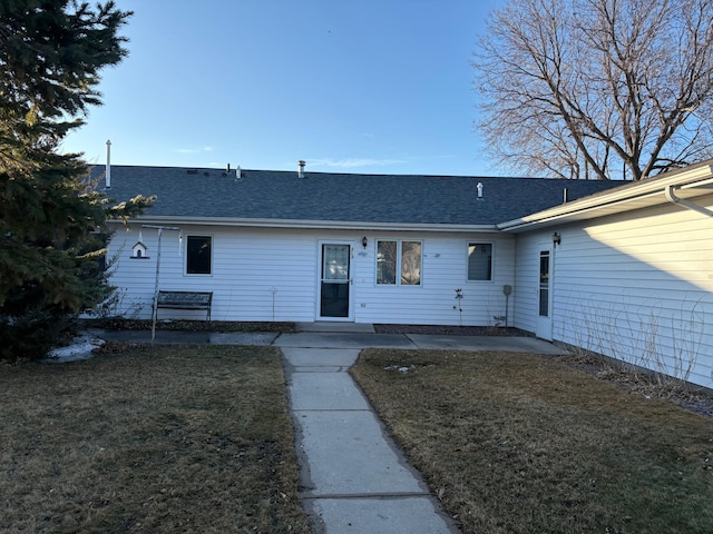 view of front of home with a patio area, roof with shingles, and a front yard