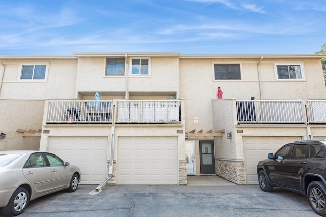 townhome / multi-family property with an attached garage, driveway, and stucco siding