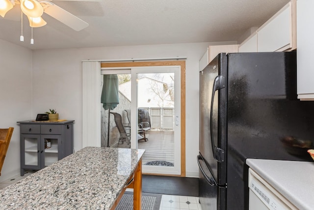 kitchen with ceiling fan, white cabinets, baseboards, light stone countertops, and freestanding refrigerator