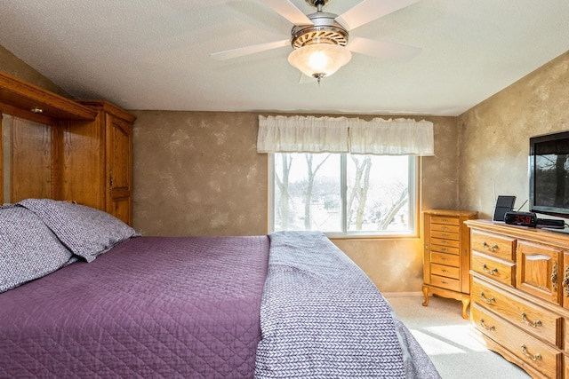 bedroom with a textured wall, a ceiling fan, baseboards, and light carpet