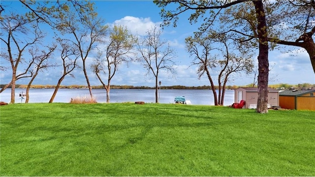 view of yard with a water view, an outdoor structure, and a storage unit