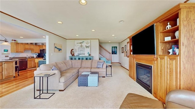 living area with recessed lighting, a glass covered fireplace, light carpet, and stairs