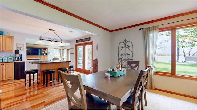 dining space featuring light wood-style flooring, baseboards, crown molding, and french doors