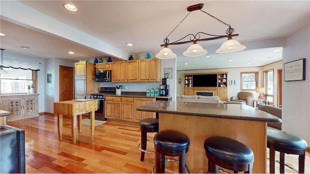 kitchen with decorative light fixtures, dark countertops, stainless steel microwave, gas stove, and open floor plan