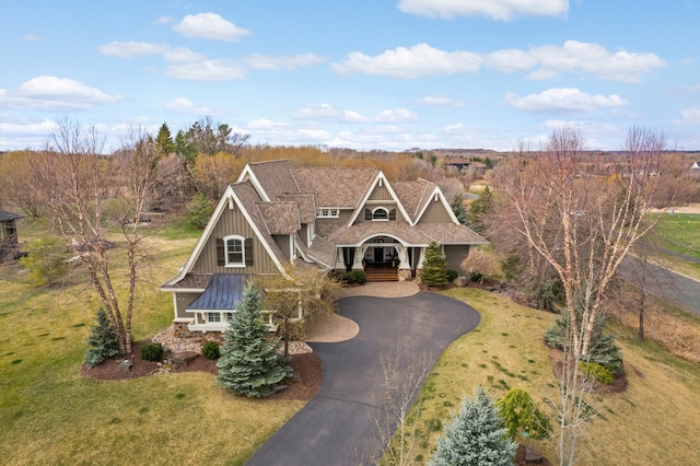 view of front facade featuring aphalt driveway, board and batten siding, a porch, and a front lawn