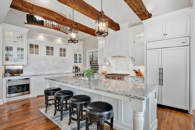 kitchen with stainless steel appliances, white cabinetry, and dark wood finished floors