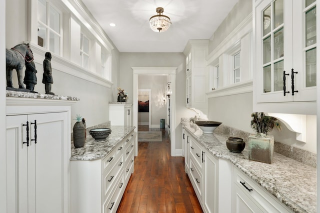 bar featuring dark wood-style flooring, a sink, and baseboards