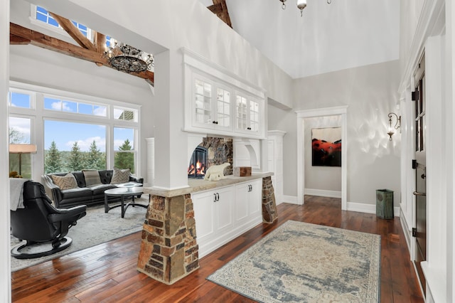 entrance foyer with a towering ceiling, a warm lit fireplace, baseboards, and dark wood-type flooring