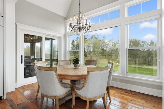 dining space featuring a notable chandelier, lofted ceiling, visible vents, hardwood / wood-style floors, and baseboards