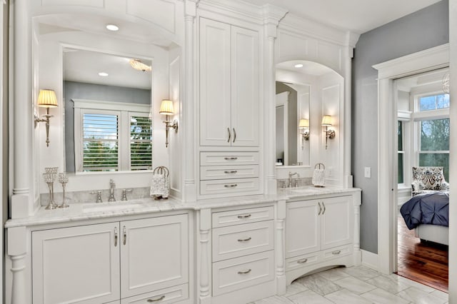 ensuite bathroom with double vanity, a wealth of natural light, and a sink