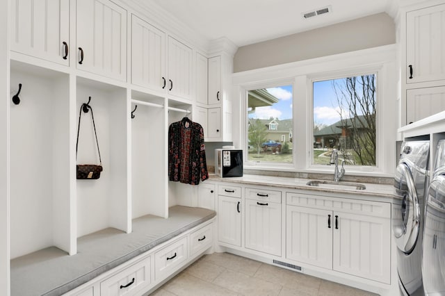 mudroom with light tile patterned floors, a sink, visible vents, and separate washer and dryer