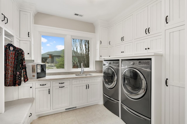 laundry room featuring visible vents, cabinet space, light tile patterned flooring, a sink, and separate washer and dryer