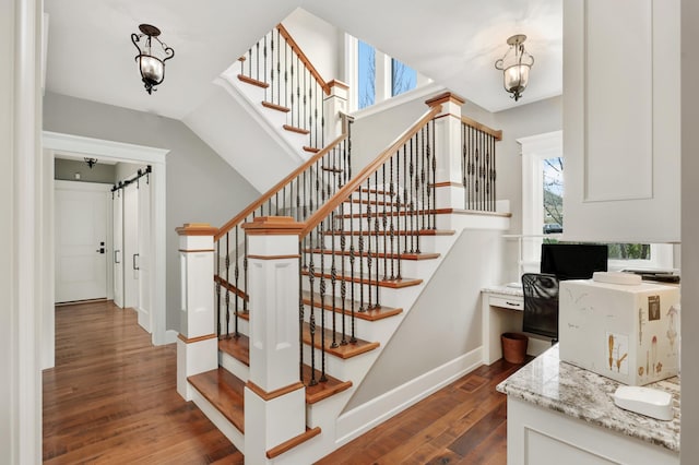 staircase featuring a barn door, visible vents, baseboards, and wood finished floors