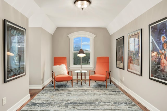 living area featuring dark wood-style floors, lofted ceiling, and baseboards