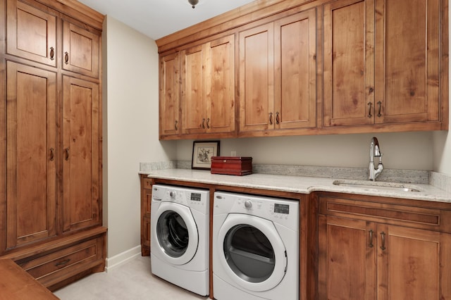 laundry room with washing machine and dryer, cabinet space, a sink, and baseboards