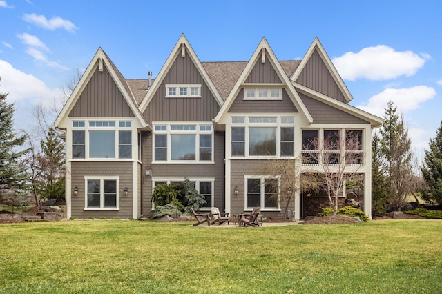 rear view of property featuring a shingled roof and a yard