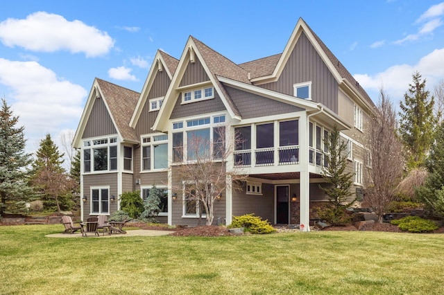 back of house featuring a shingled roof, a sunroom, a lawn, and a patio