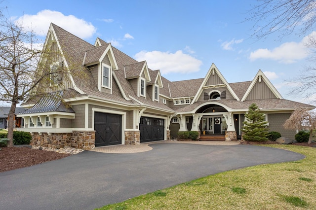 view of front of property with driveway, stone siding, an attached garage, and a shingled roof