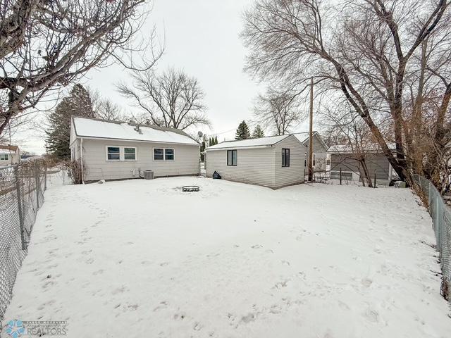 snow covered property featuring a fenced backyard and an outbuilding