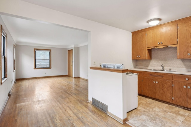 kitchen featuring brown cabinetry, visible vents, a sink, and decorative backsplash