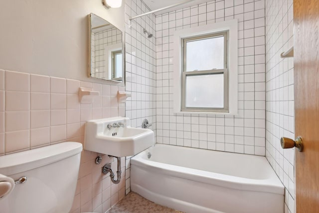 bathroom with toilet, bathing tub / shower combination, and tile walls