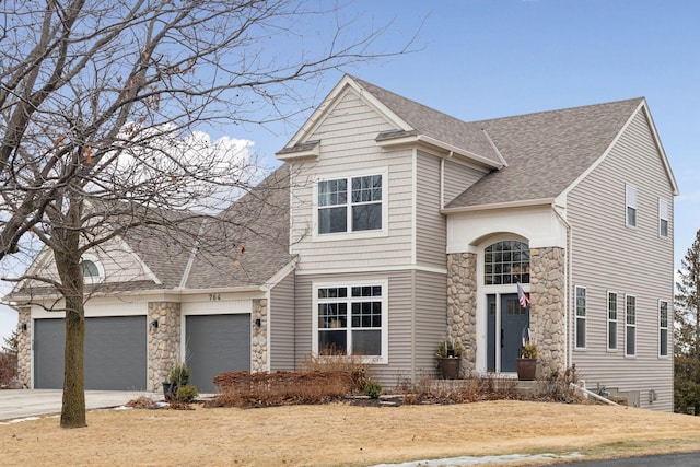 traditional-style home featuring a shingled roof, stone siding, concrete driveway, and a garage