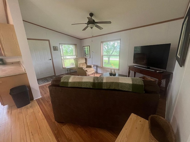 living area featuring lofted ceiling, a ceiling fan, crown molding, and wood finished floors