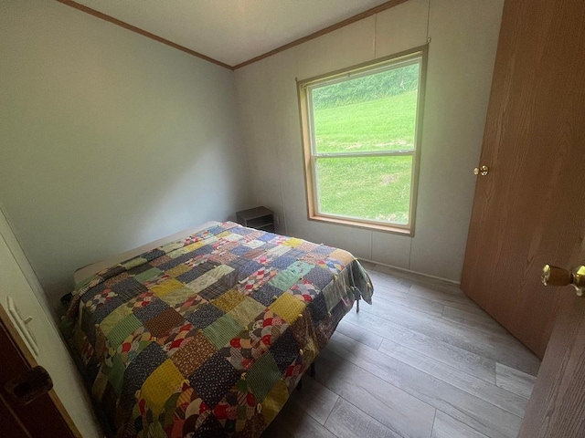 bedroom featuring ornamental molding and light wood finished floors