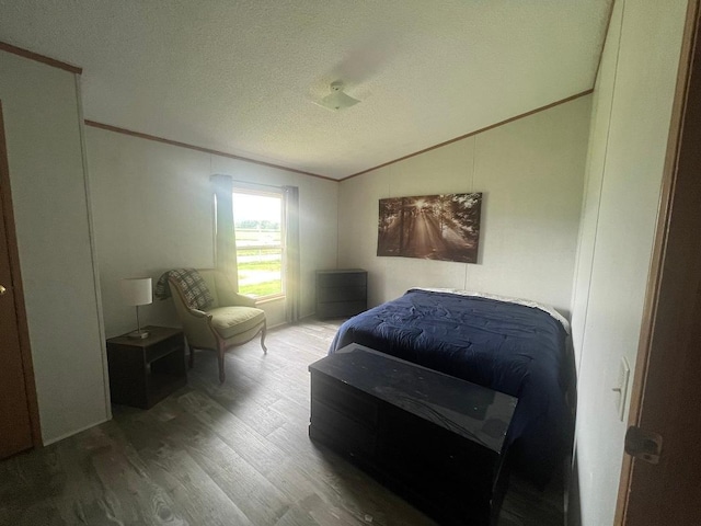 bedroom featuring crown molding, a textured ceiling, vaulted ceiling, and wood finished floors