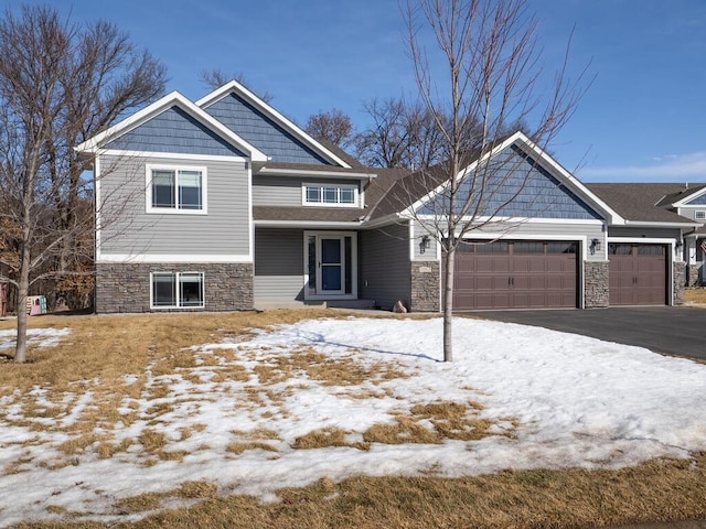 craftsman-style house with aphalt driveway, stone siding, and an attached garage