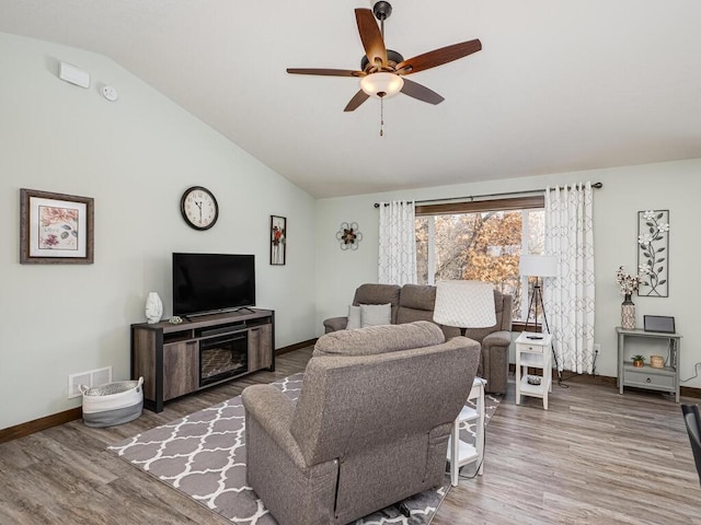 living room with visible vents, ceiling fan, vaulted ceiling, wood finished floors, and baseboards