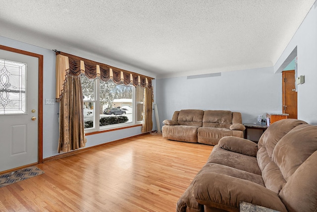 living area with a textured ceiling, baseboards, and wood finished floors