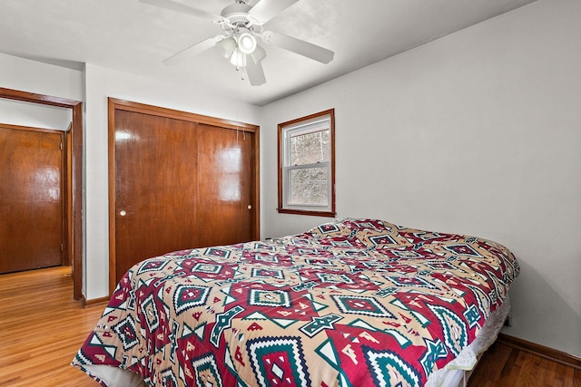 bedroom with a closet, ceiling fan, baseboards, and wood finished floors