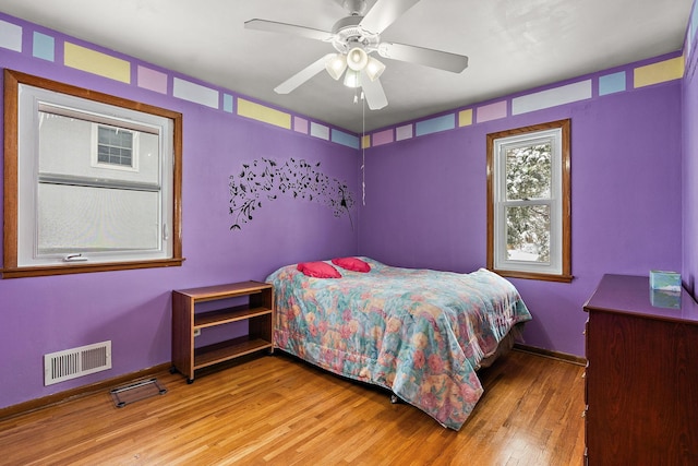 bedroom featuring ceiling fan, wood-type flooring, visible vents, and baseboards