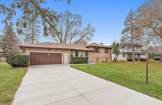 tri-level home with brick siding, a chimney, an attached garage, a front yard, and driveway