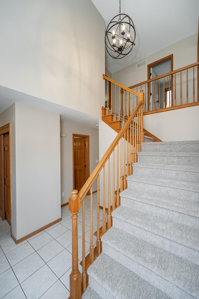 stairs featuring visible vents, baseboards, an inviting chandelier, a high ceiling, and tile patterned flooring