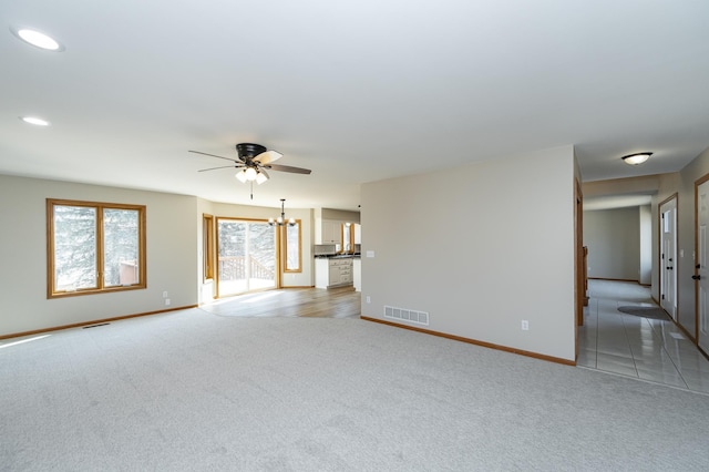 unfurnished living room with ceiling fan with notable chandelier, recessed lighting, light colored carpet, and visible vents