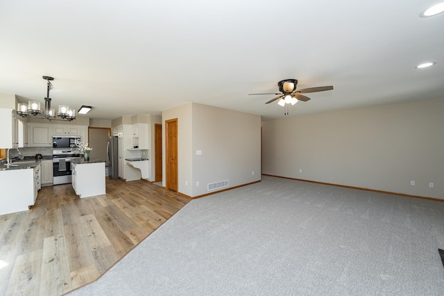 kitchen with baseboards, visible vents, stainless steel appliances, dark countertops, and ceiling fan with notable chandelier