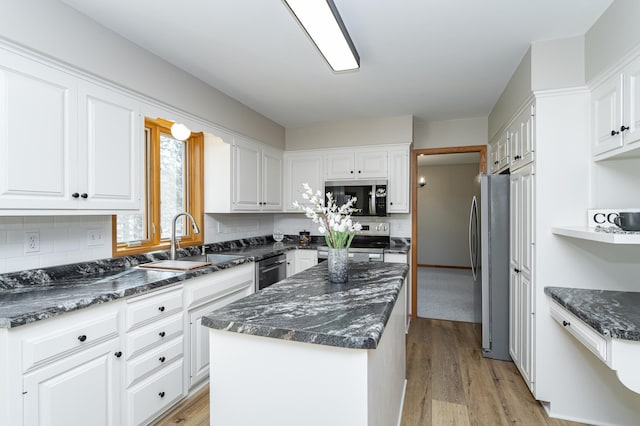 kitchen with a kitchen island, a sink, white cabinets, light wood-style floors, and appliances with stainless steel finishes